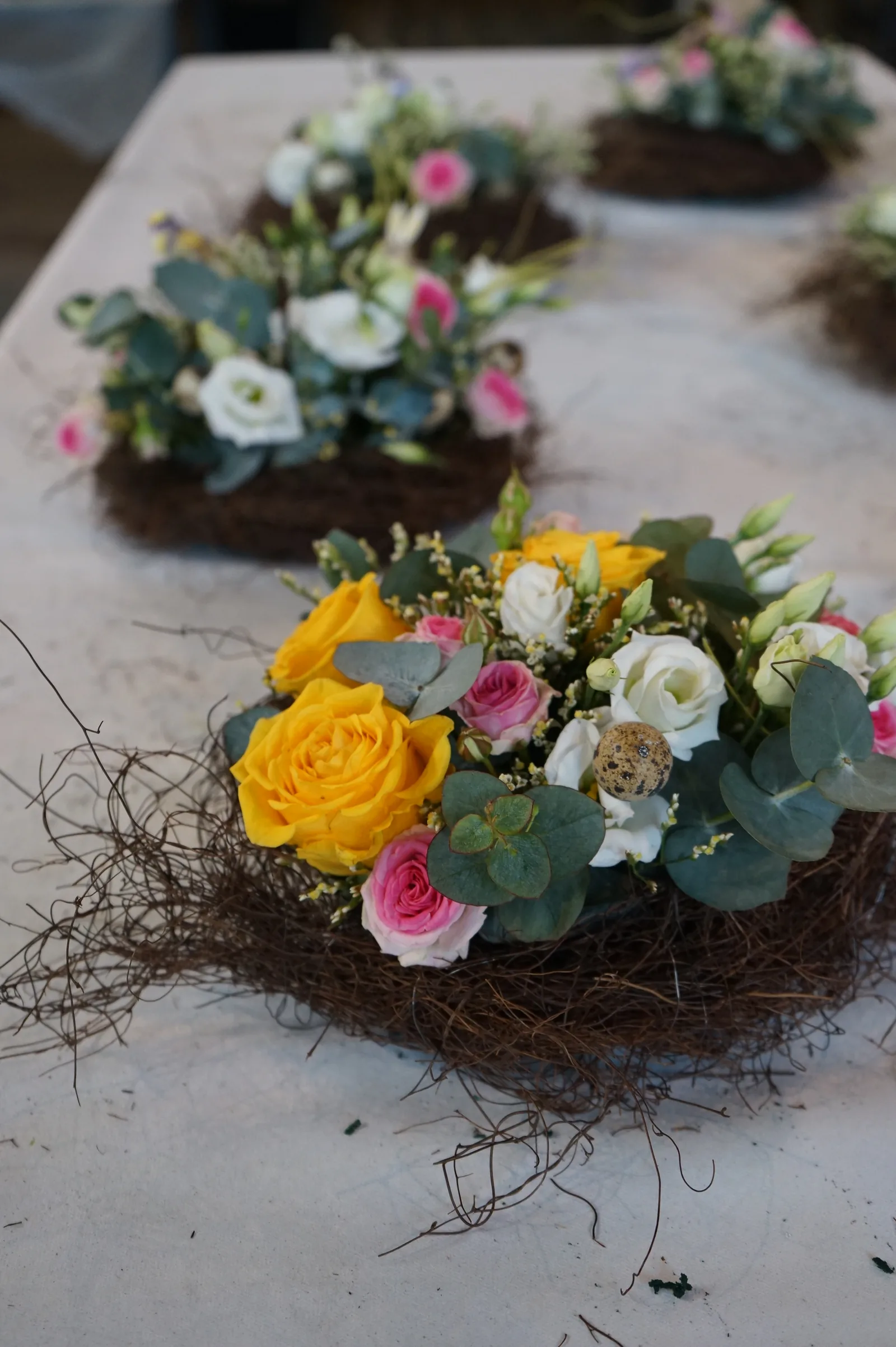 Nidi di rami con rose gialle e rosa, lisianthus ed eucalipto sul tavolo del corso di Pasqua