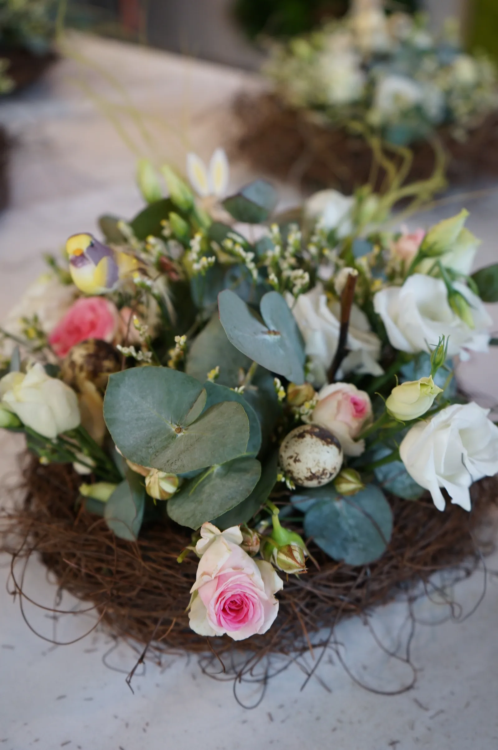 Un nido pasquale con rose rosa e bianche, lisianthus ed eucalipto