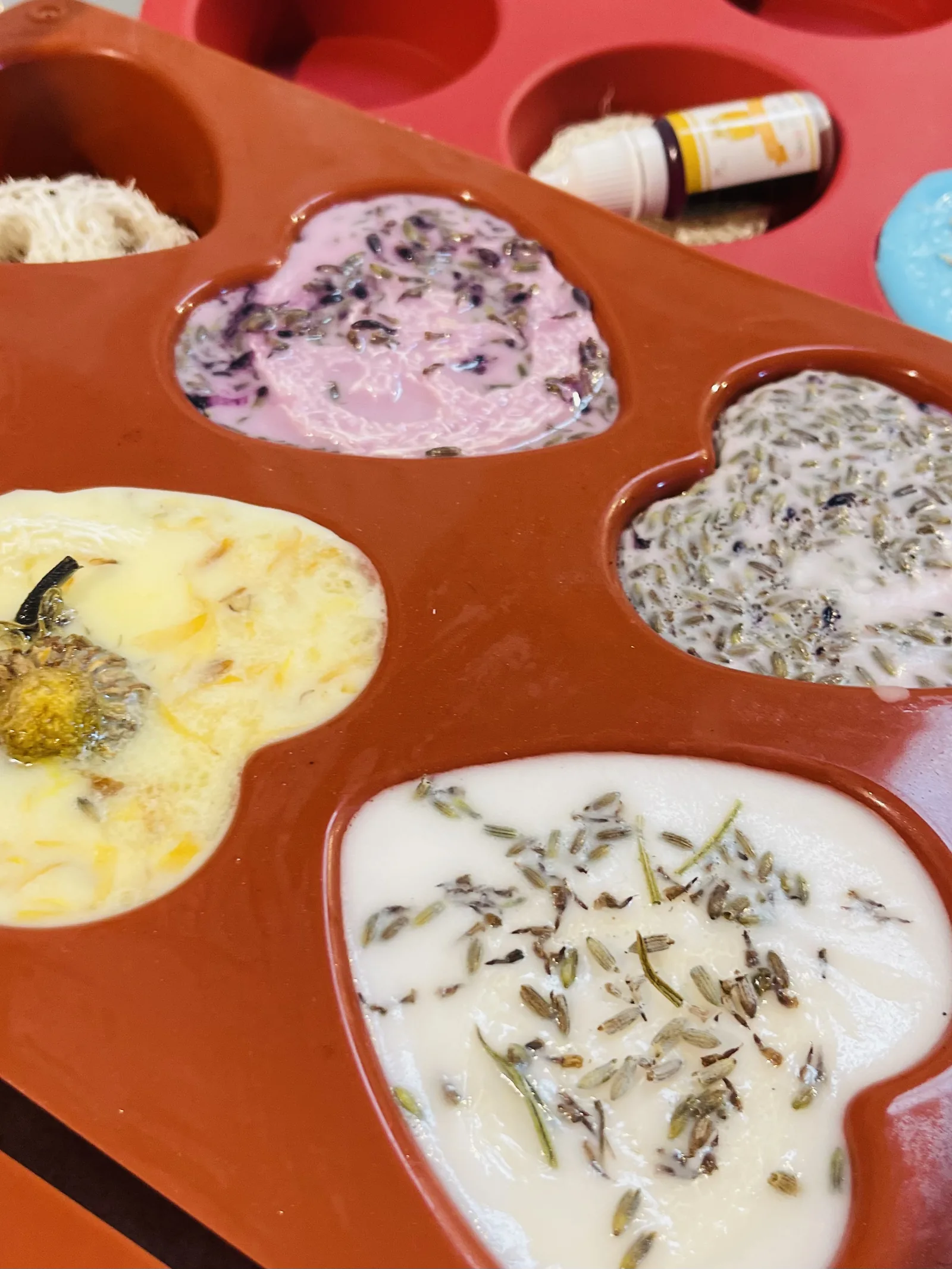 Stampi a cuore riempiti di sapone chiaro e rosa, con lavanda e fiori secchi