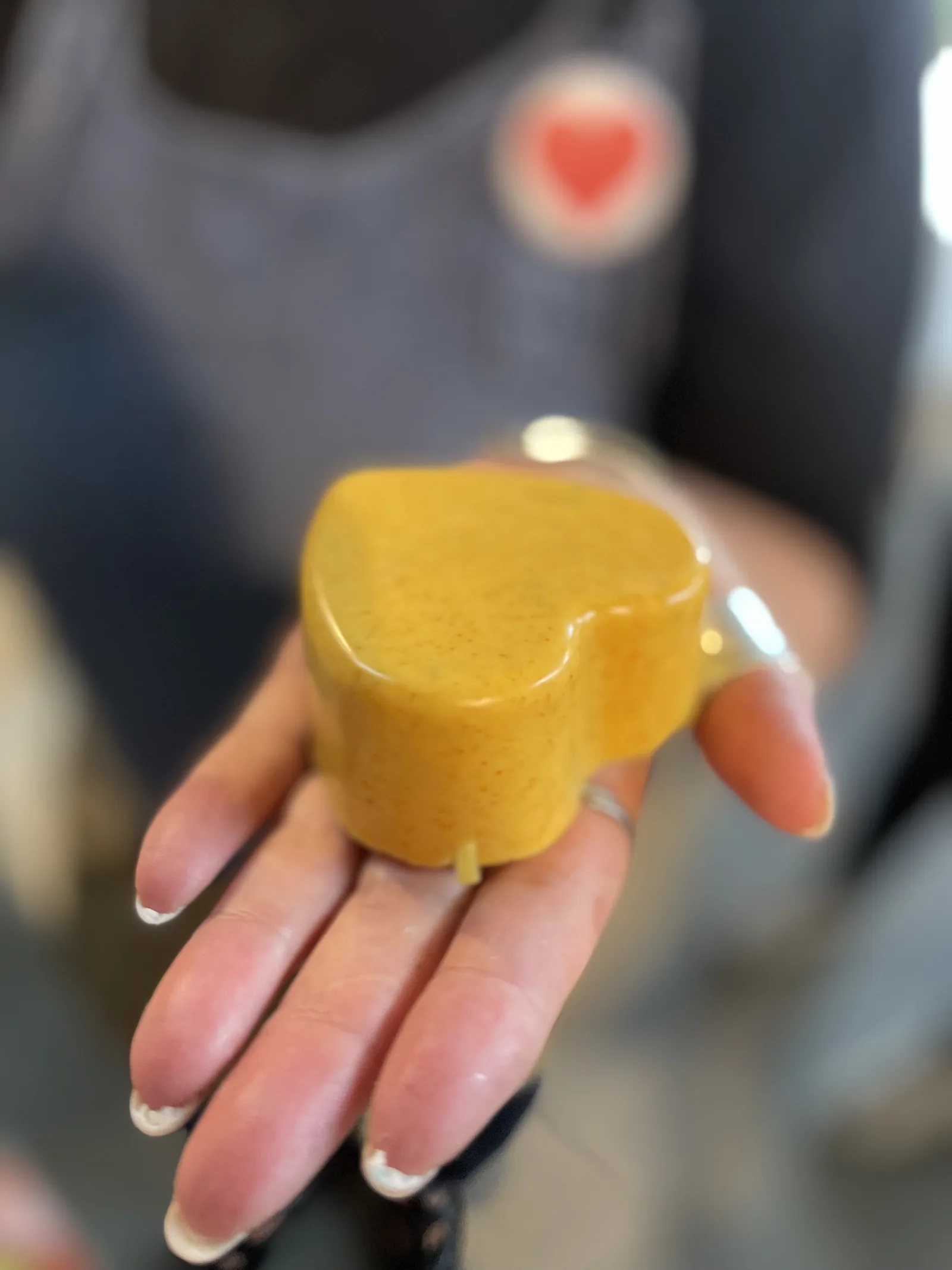 Un sapone giallo a forma di cuore appoggiato sul palmo di una mano