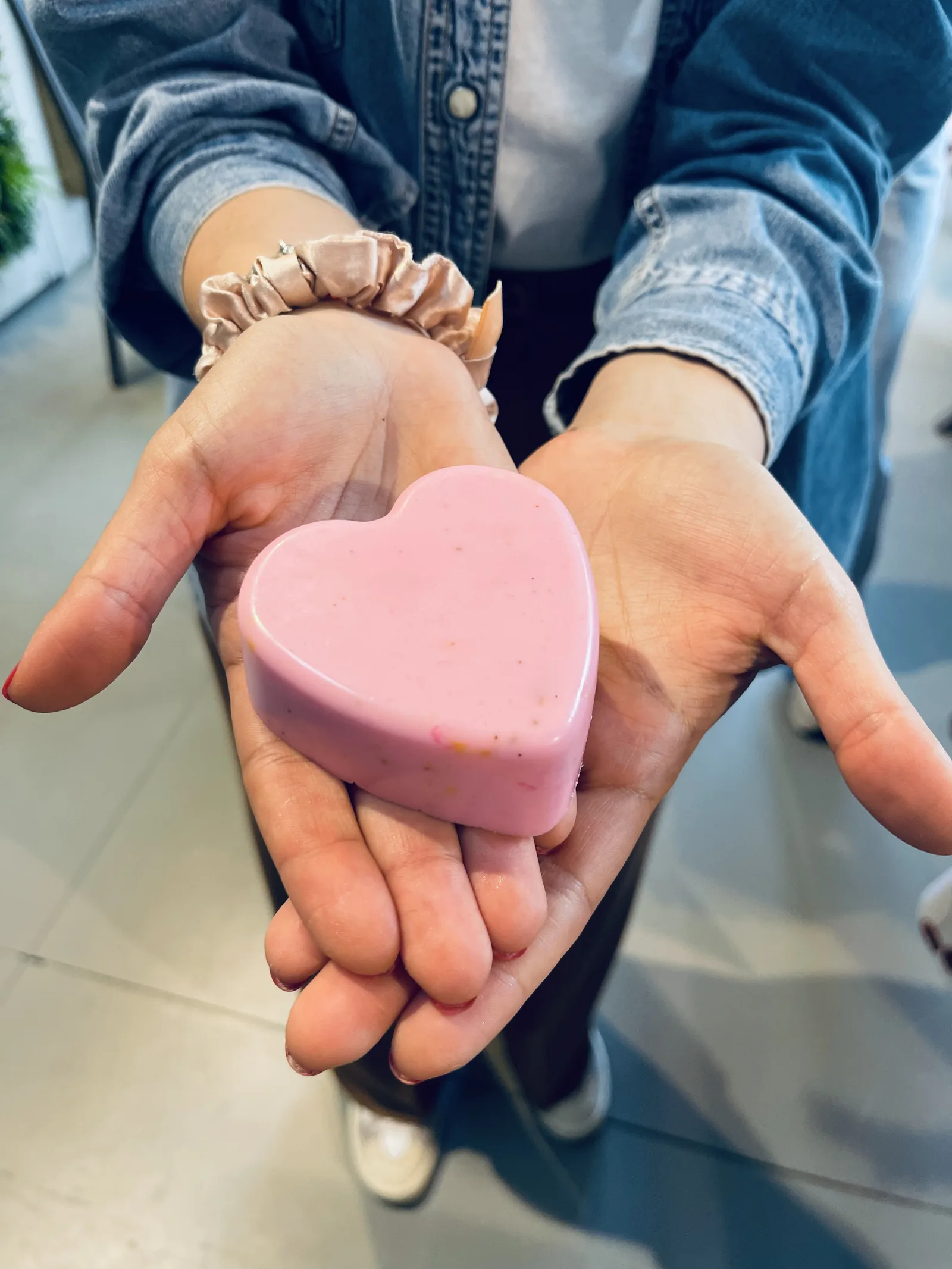 Un sapone rosa a forma di cuore nel palmo di due mani