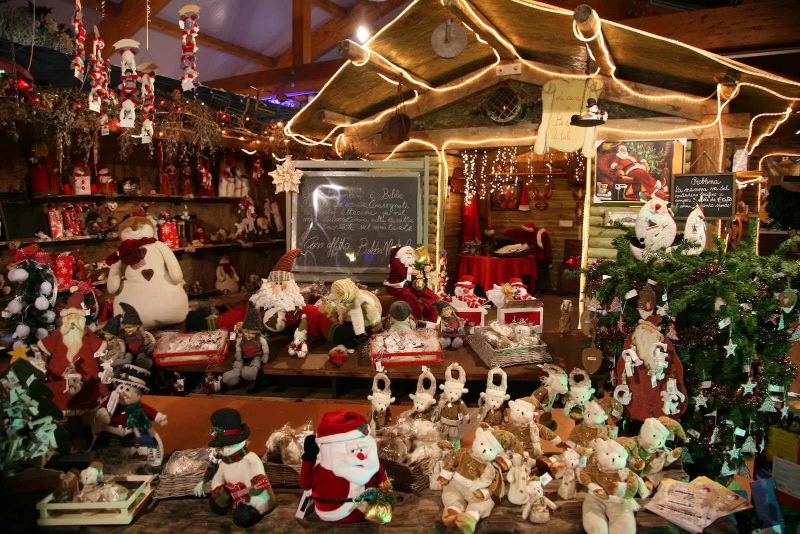 Casetta di legno illuminata piena di pupazzi di neve, orsetti e Babbo Natale