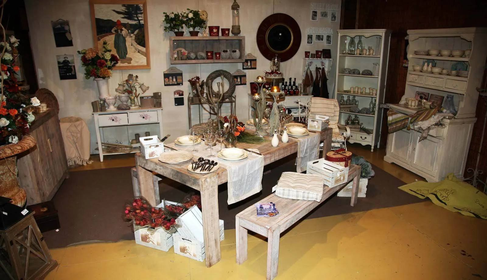 Ambiente in legno bianco con un tavolo apparecchiato, credenze e fiori rossi