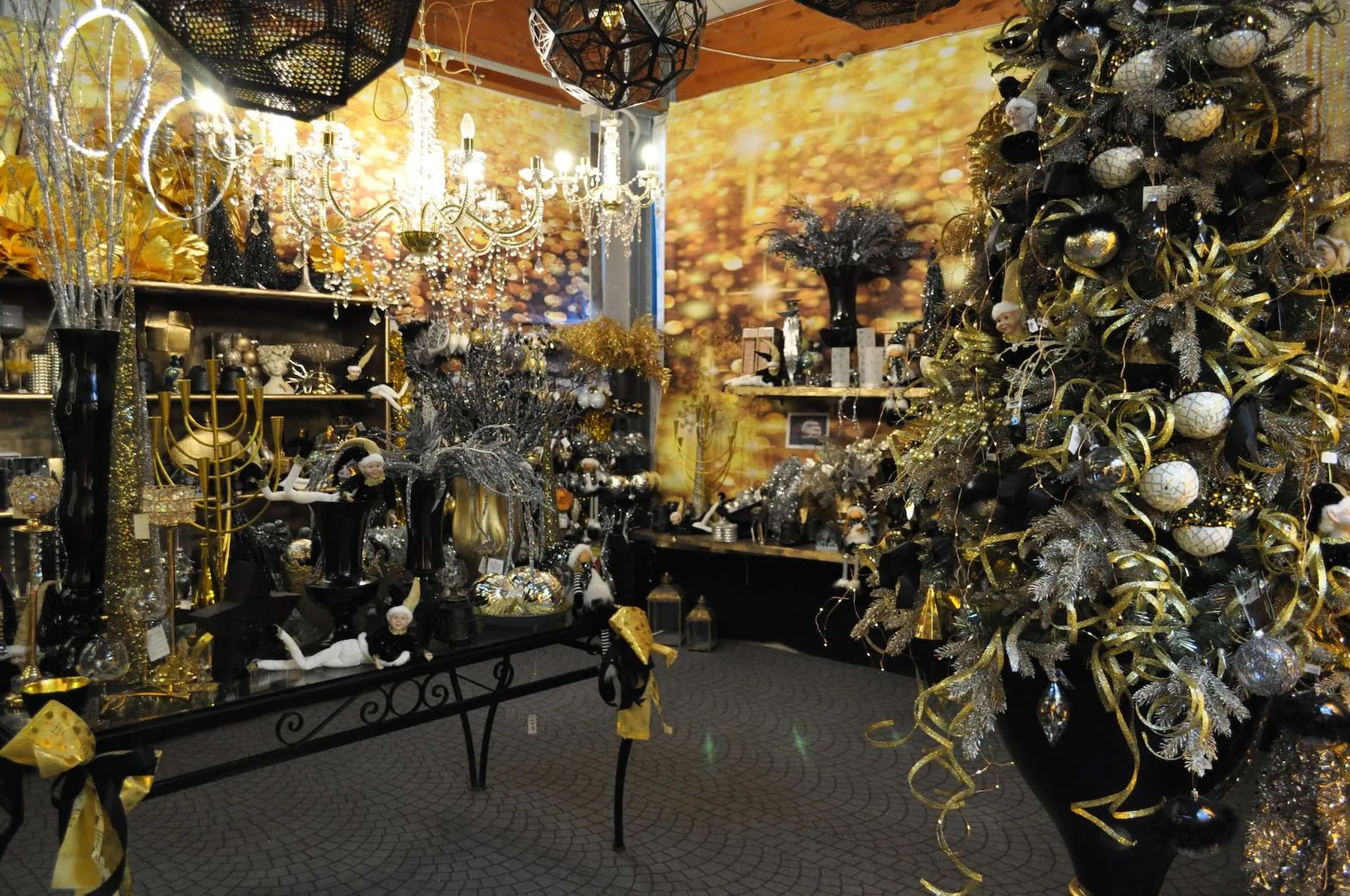 Sala di decorazioni natalizie in oro e nero, con lampadari di cristallo e un albero addobbato