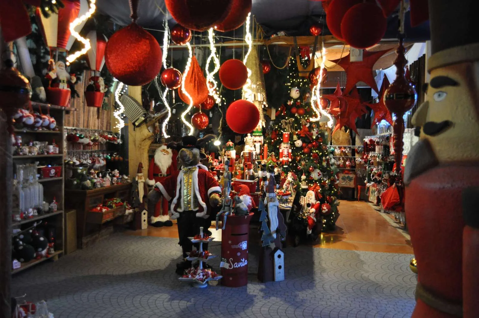 Corsia di decorazioni rosse con sfere giganti appese, Babbo Natale e un grande schiaccianoci