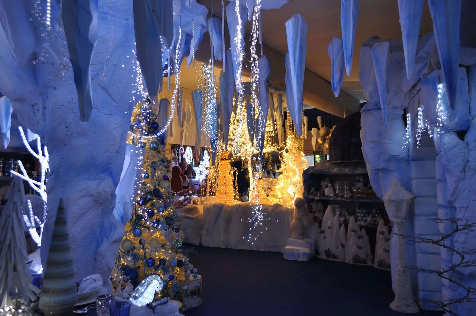 Grotta di ghiaccio con stalattiti bianche, alberi e casette illuminate