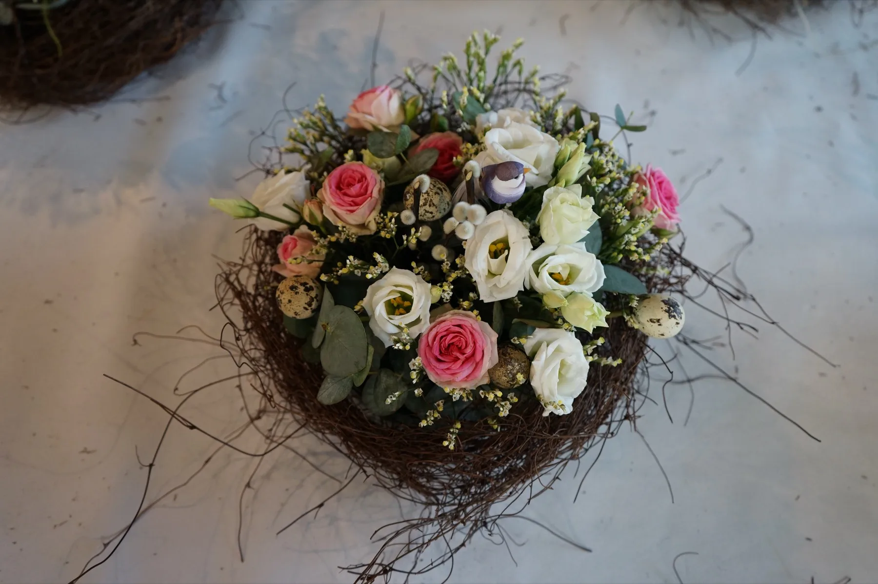 Un nido di rami con rose e lisianthus visto dall'alto sul tavolo