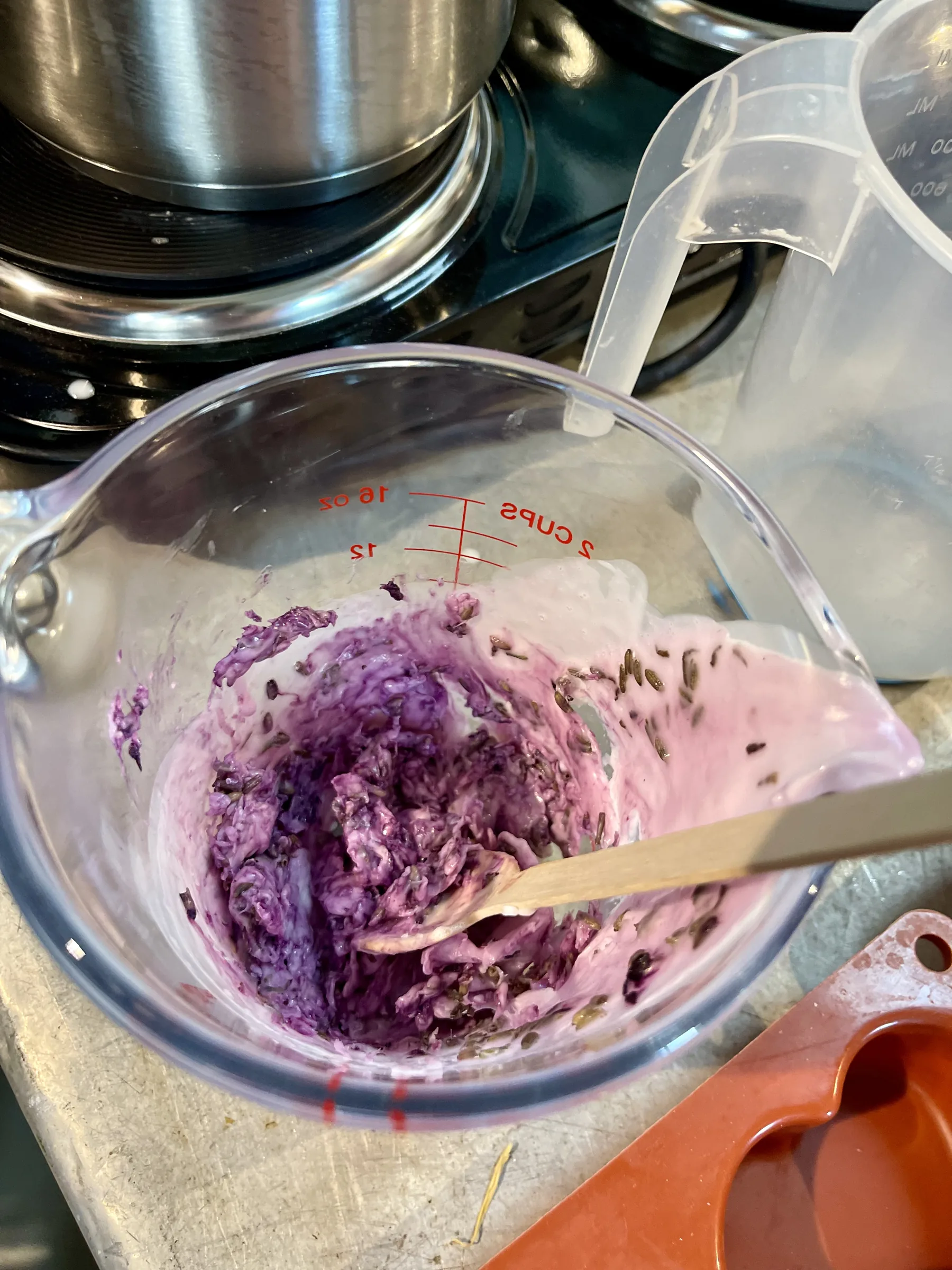 Impasto di sapone viola con i fiori di lavanda in una caraffa graduata
