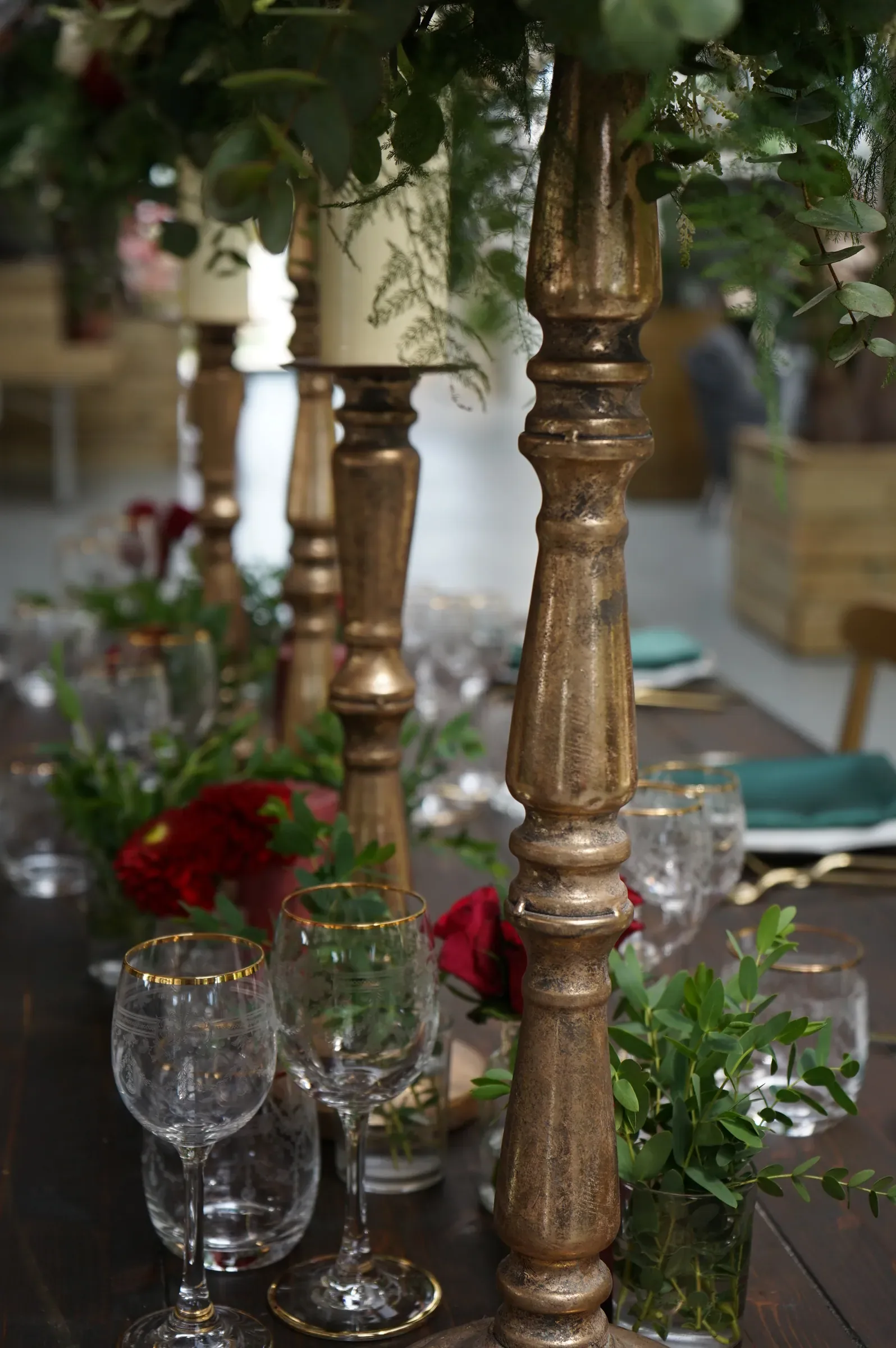 Candelieri di legno dorato con rose rosse e foglie verdi, fra i calici di cristallo