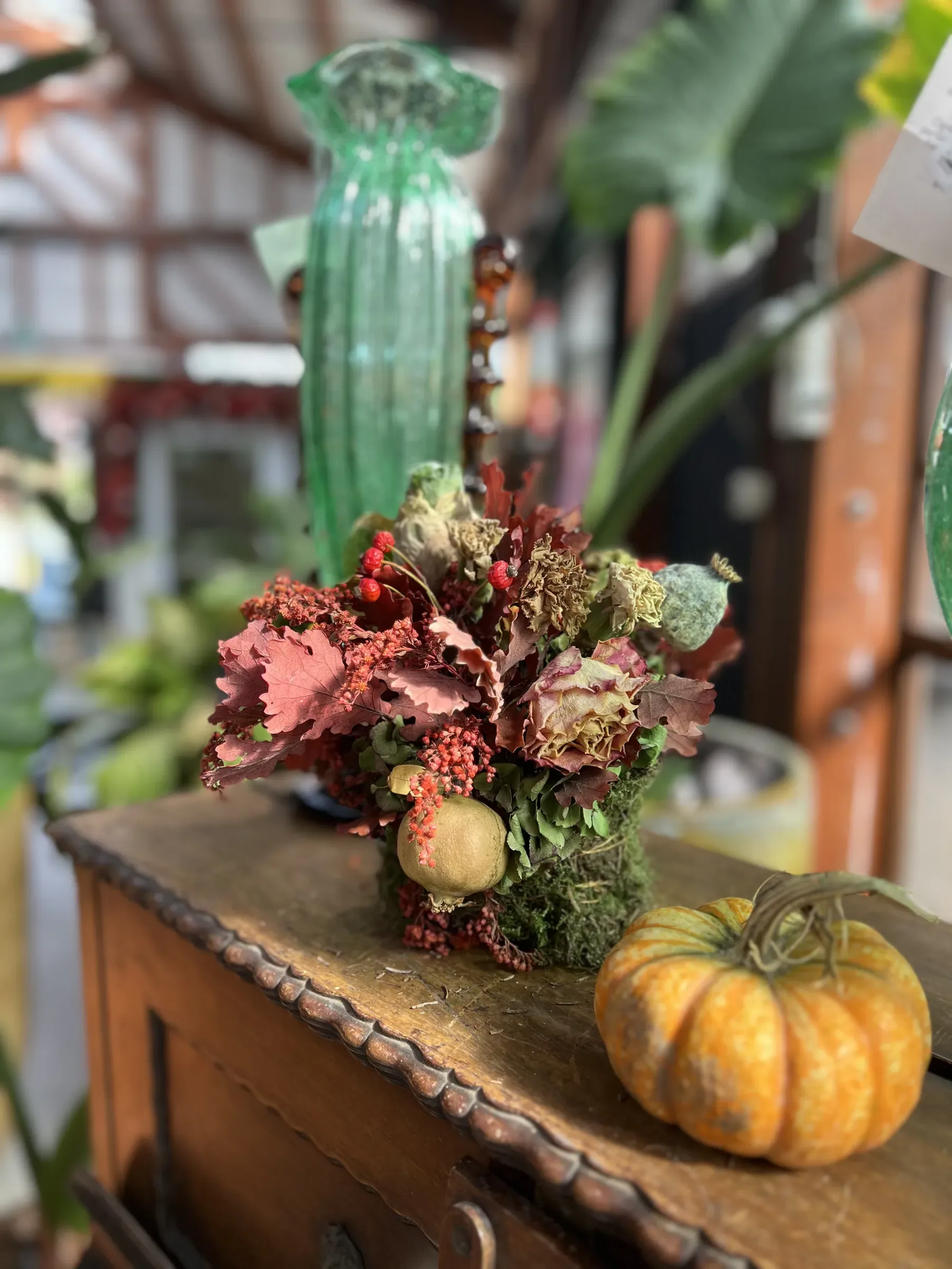 Composizione di foglie rosse, bacche e melograni con una zucca arancione, su un mobile di legno scolpito