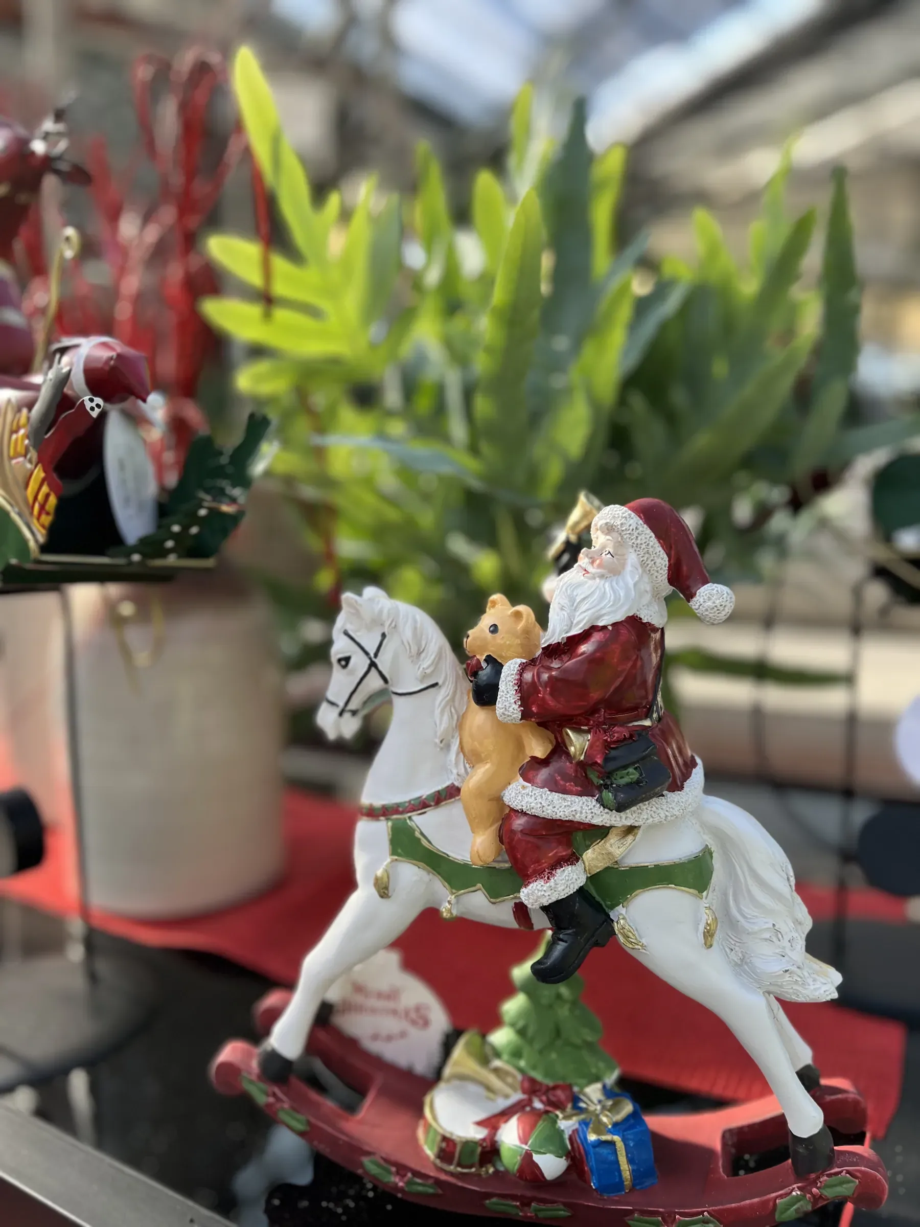 Statuina di Babbo Natale con un orsetto in sella a un cavallo a dondolo bianco