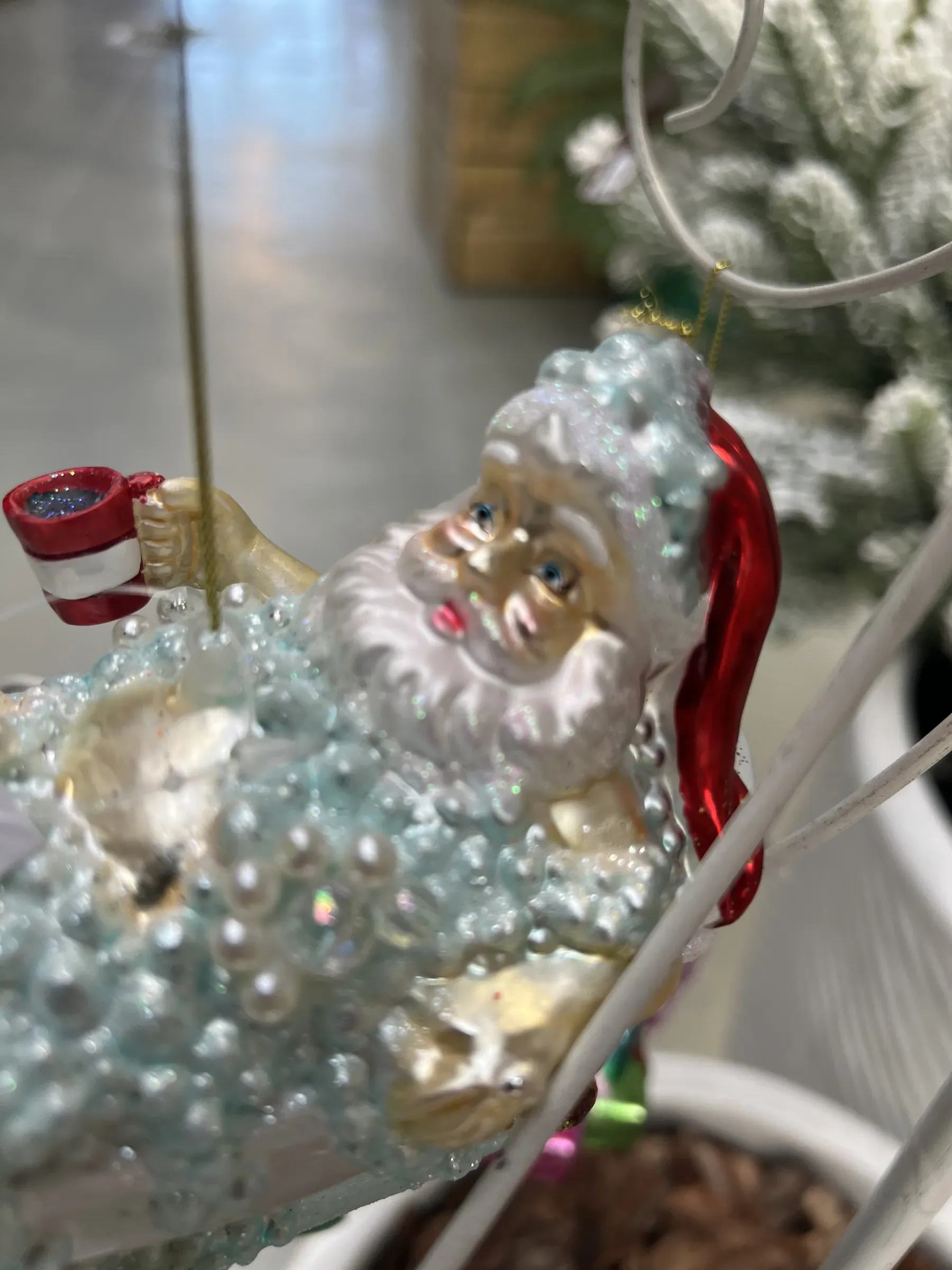 Addobbo di vetro a forma di Babbo Natale nella vasca, con la tazza in mano, appeso a un ramo