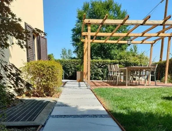Dopo: pergola in legno sulla nuova pedana in ipe con il tavolo, accanto a un camminamento in lastre