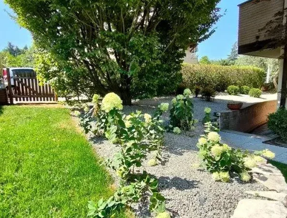 Dopo: prato e aiuola di ortensie bianche su granulato grigio, accanto a una scala in pietra