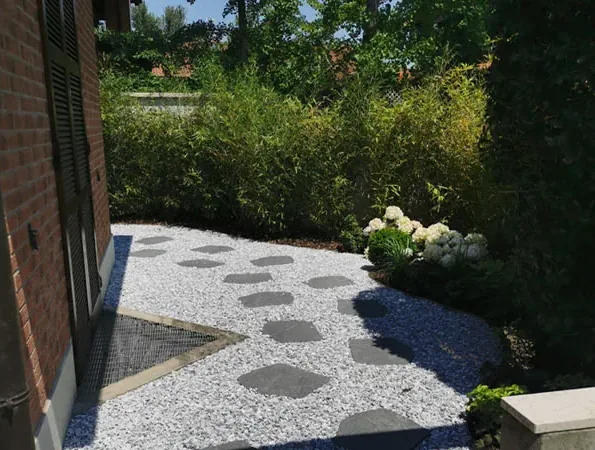 Dopo: passi in pietra su ghiaia bianca, con ortensie bianche e siepe lungo il muro in mattoni