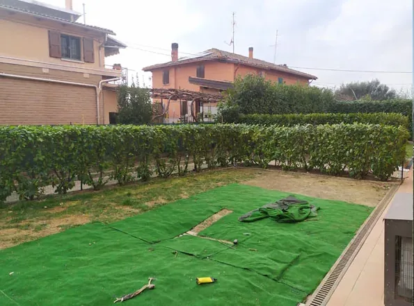 Prima: un telo verde steso sul terreno con attrezzi da lavoro, davanti alla siepe