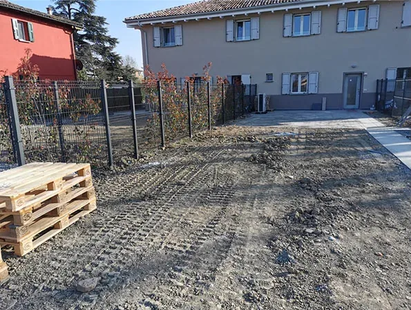Prima: terreno di cantiere davanti alla villetta, con i bancali accatastati a sinistra