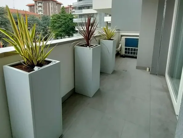 Dopo: fioriere alte grigio chiaro con cordyline lungo il parapetto dello stesso terrazzo