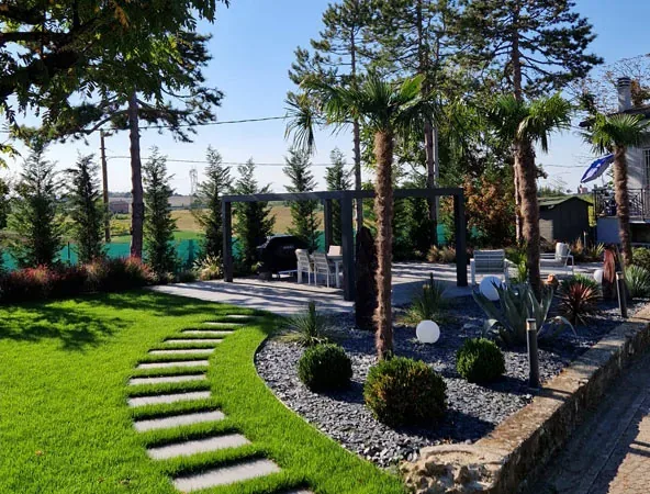 Dopo: prato con un camminamento di lastre, aiuole di scaglie d'ardesia, arbusti a palla e palme, con la pergola sul fondo