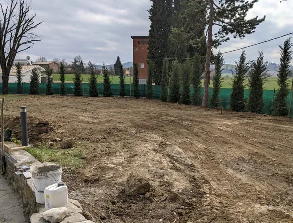 Prima: terreno smosso davanti a una fila di cipressi, prima dei lavori