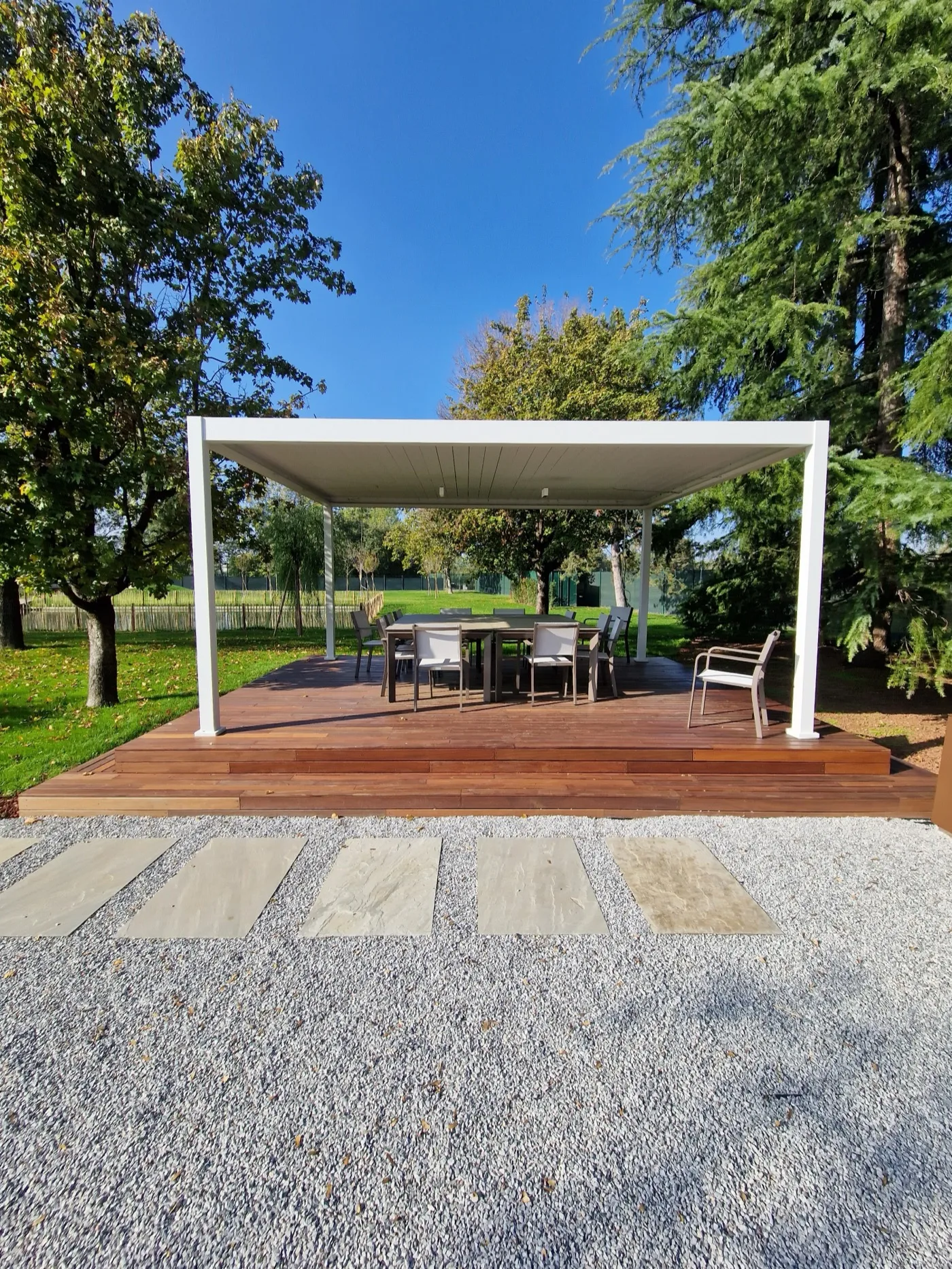 Pergola bianca su pavimentazione in legno con camminamento in pietra