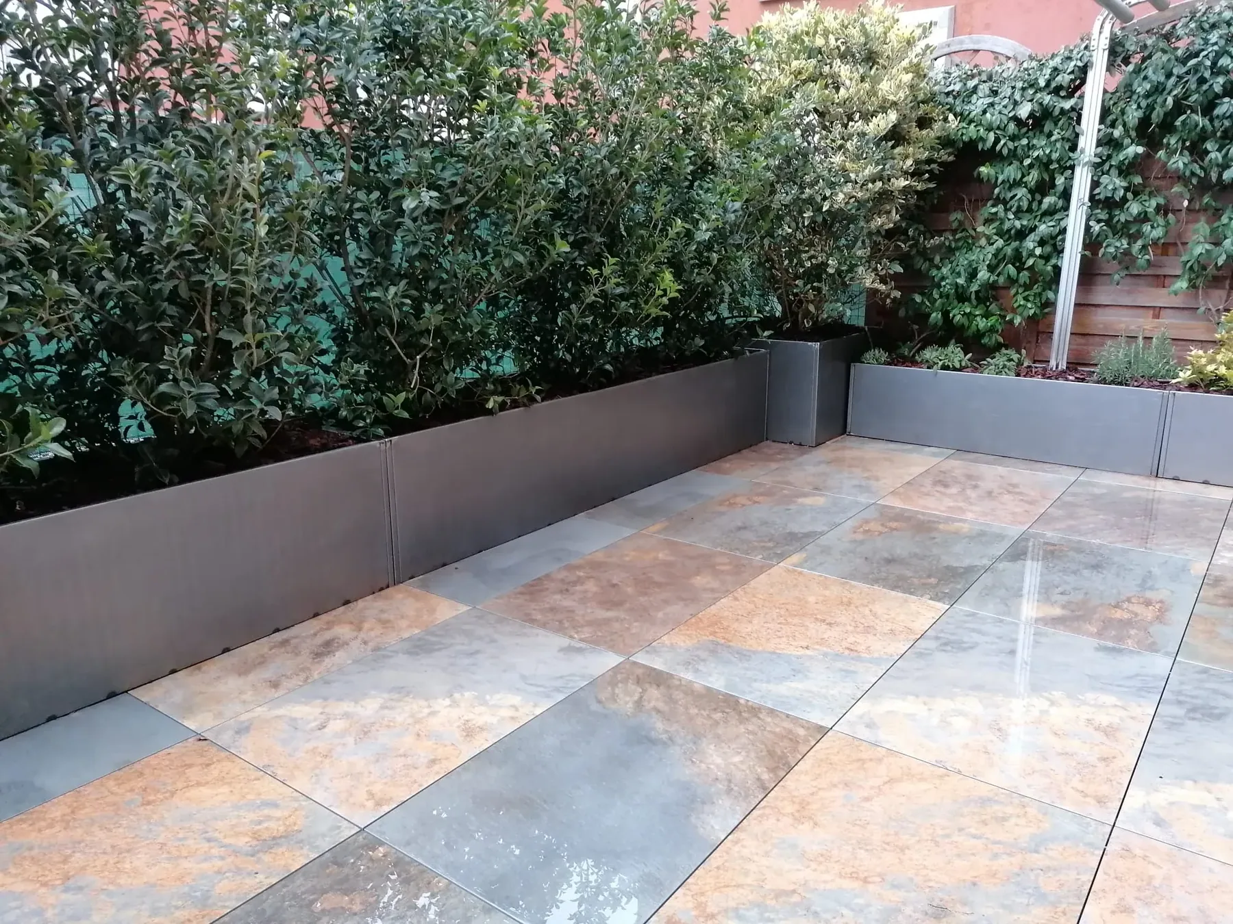 Terrazzo pavimentato in grandi lastre dai toni dell'ardesia, con fioriere grigie di lauro lungo il parapetto