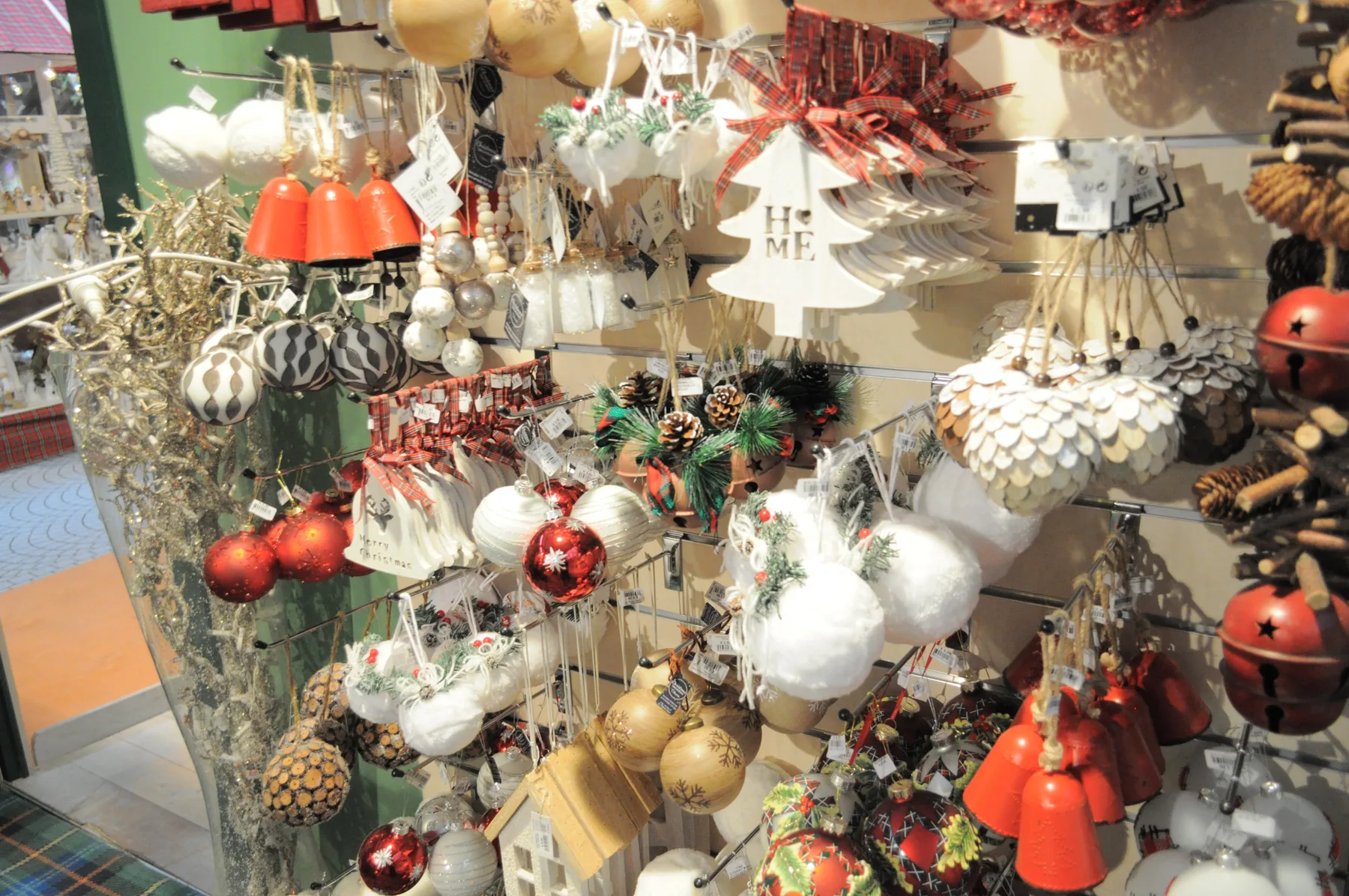Decorazioni rosse e bianche appese: palline, campanelle, alberelli di legno e pigne