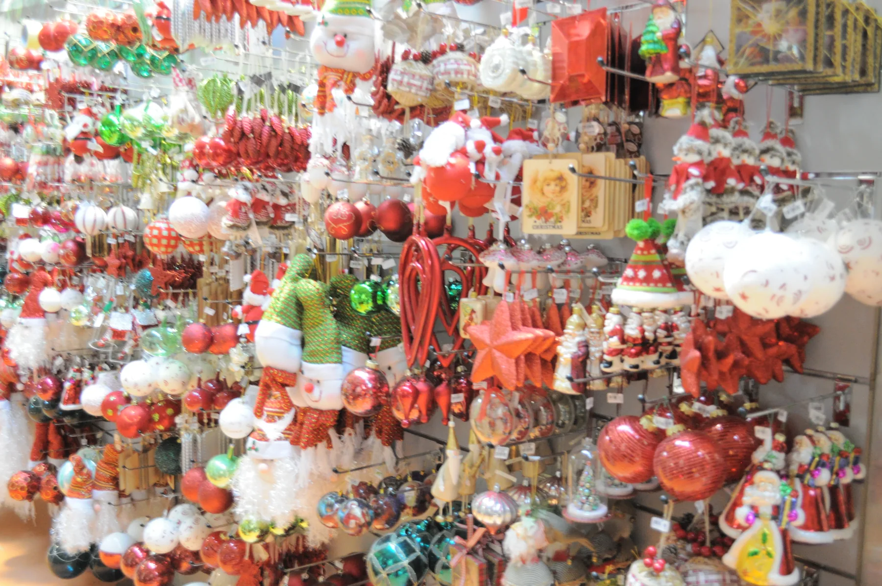 Parete di decorazioni rosse e bianche appese: palline, pupazzi di neve e Babbi Natale