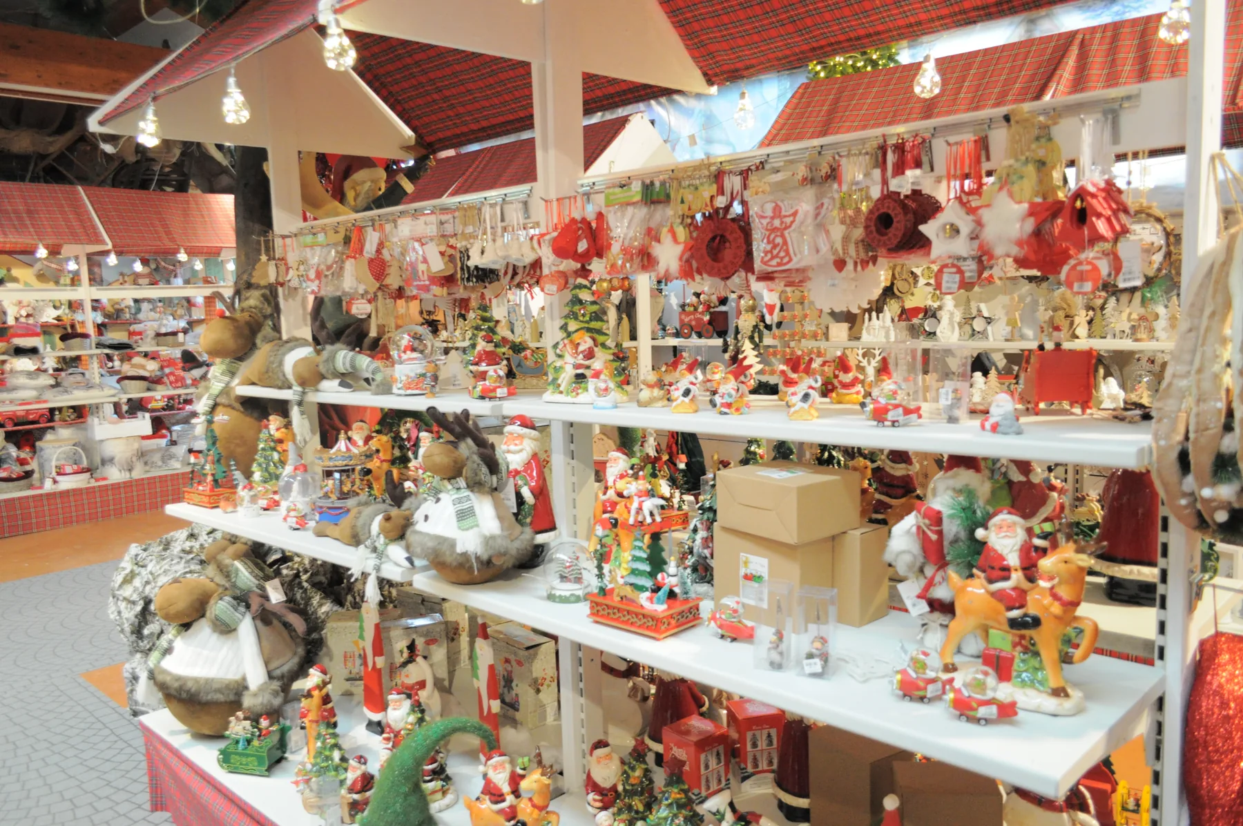 Bancarelle di decorazioni rosse e bianche con il tetto a tenda e i Babbi Natale sui ripiani