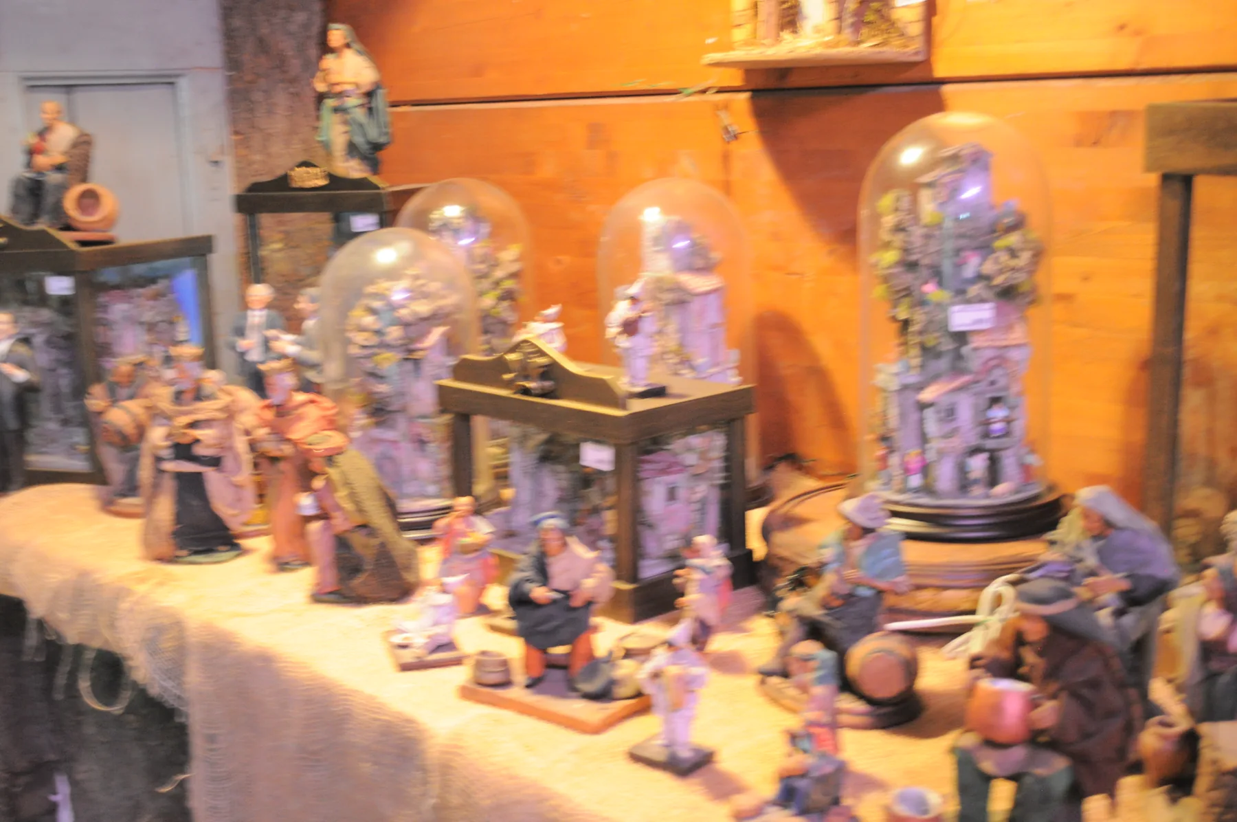 Statuine da presepe di pastori e contadini, alcune sotto campane di vetro, su un tavolo