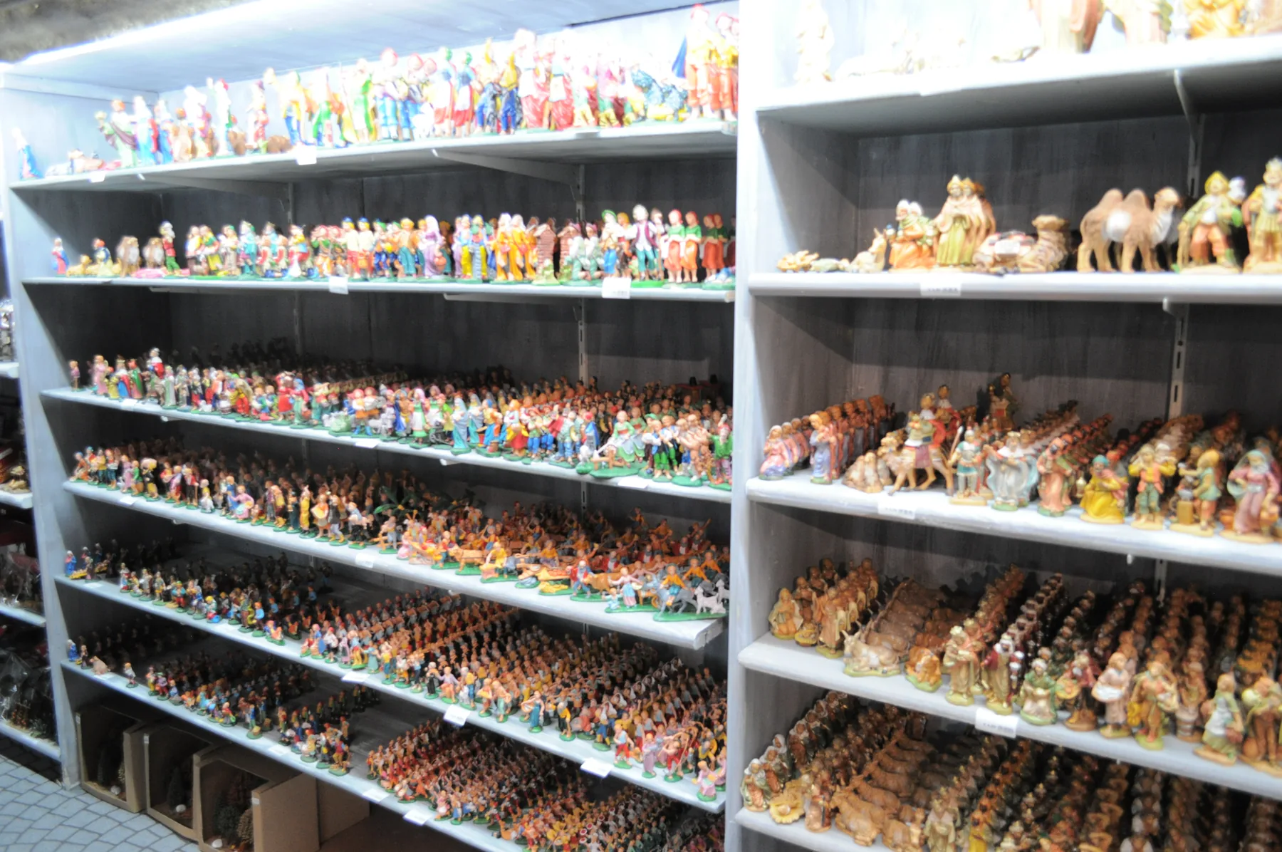 Scaffali pieni di statuine per il presepe: pastori, Re Magi, cammelli e animali