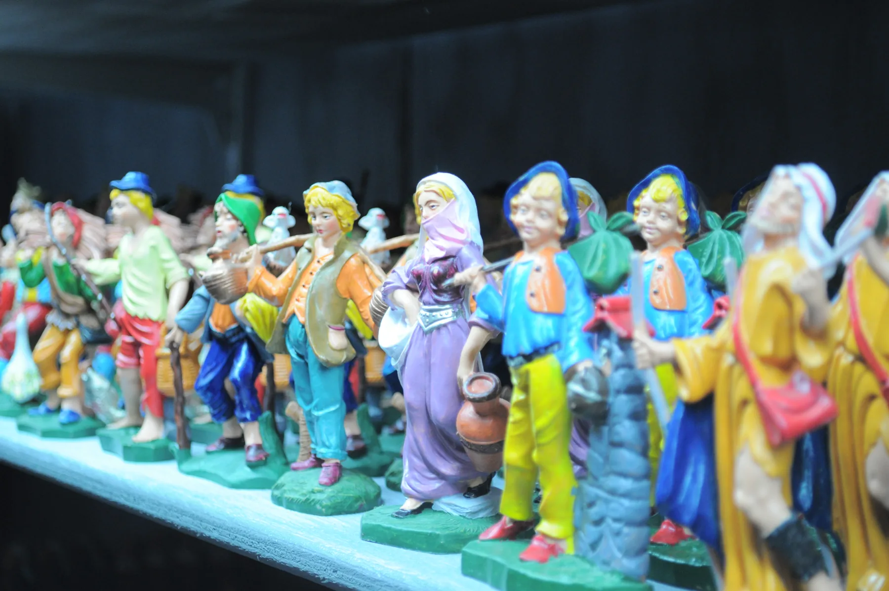 Fila di statuine colorate da presepe con vesti e fazzoletti dipinti