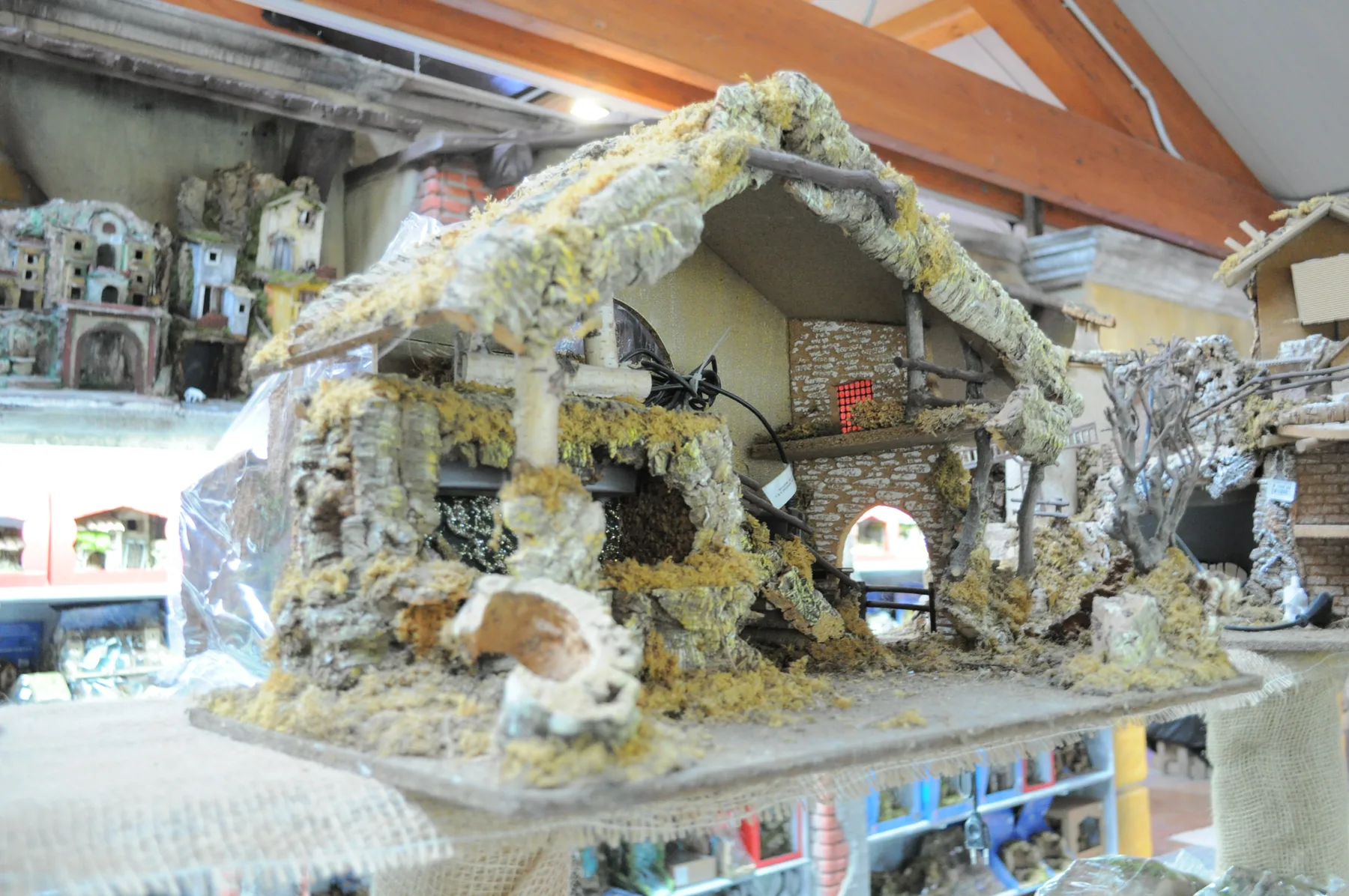 Capanna del presepe con il tetto di paglia e muschio, esposta su un banco