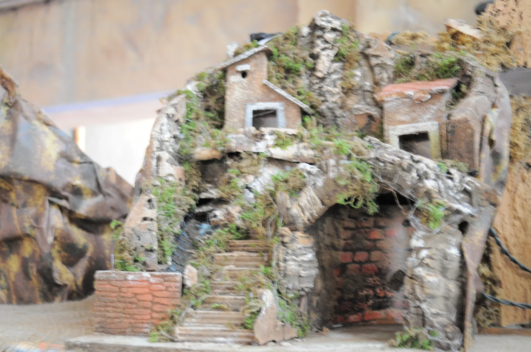 Grotta da presepe in roccia con muschio, una scalinata e una casetta in cima