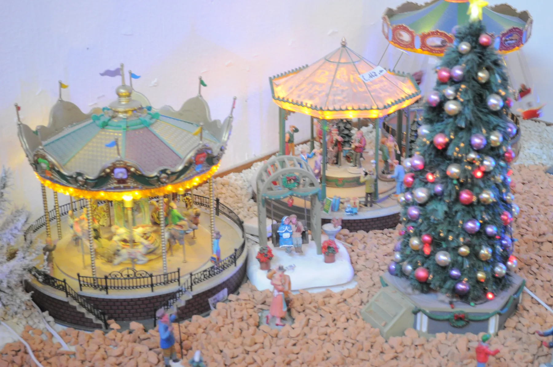 Giostre in miniatura illuminate accanto a un piccolo albero di Natale addobbato