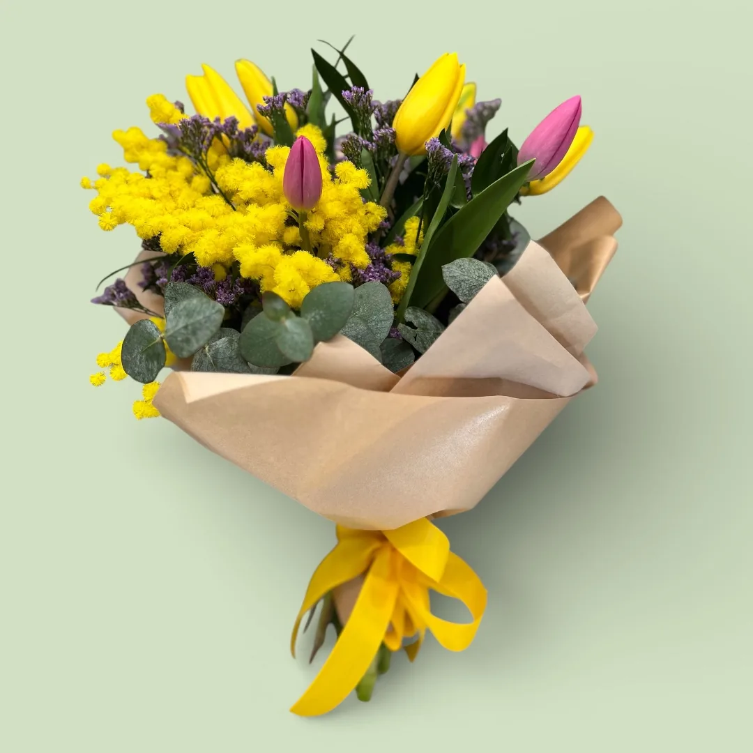 Mazzo di mimosa con tulipani rosa e gialli, limonium viola ed eucalipto, incartato