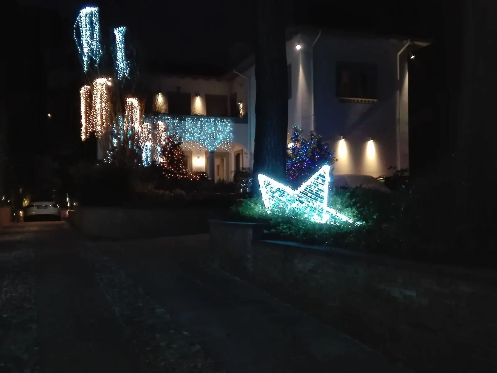 Villa di notte con cascate di luci sugli alberi del giardino e una stella luminosa sul prato