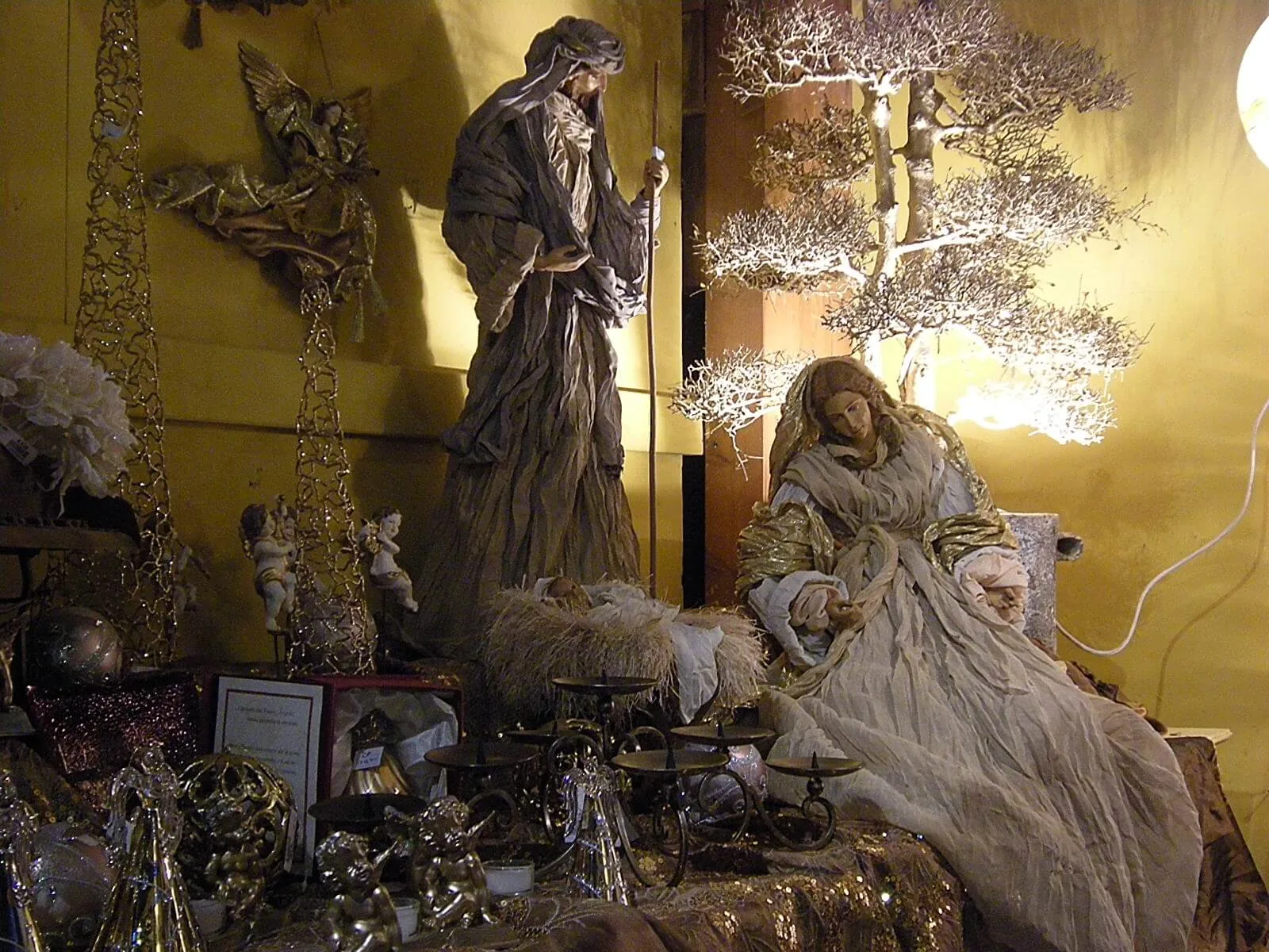 Presepe con le grandi statue di Maria e Giuseppe davanti a un albero bianco luminoso