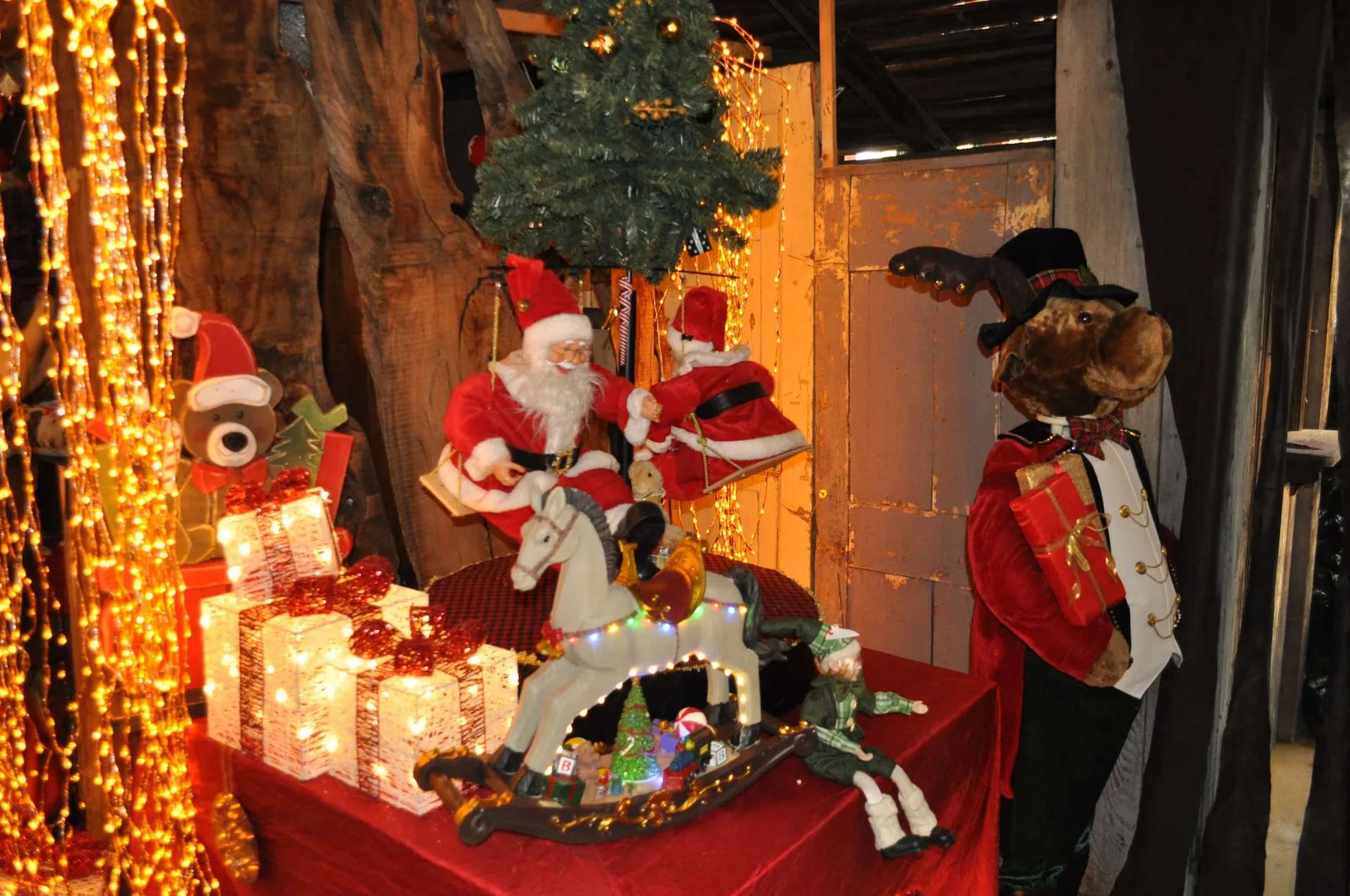 Pupazzi di Babbo Natale su un cavallo a dondolo, con pacchi luminosi, un orsetto e un alce in frac