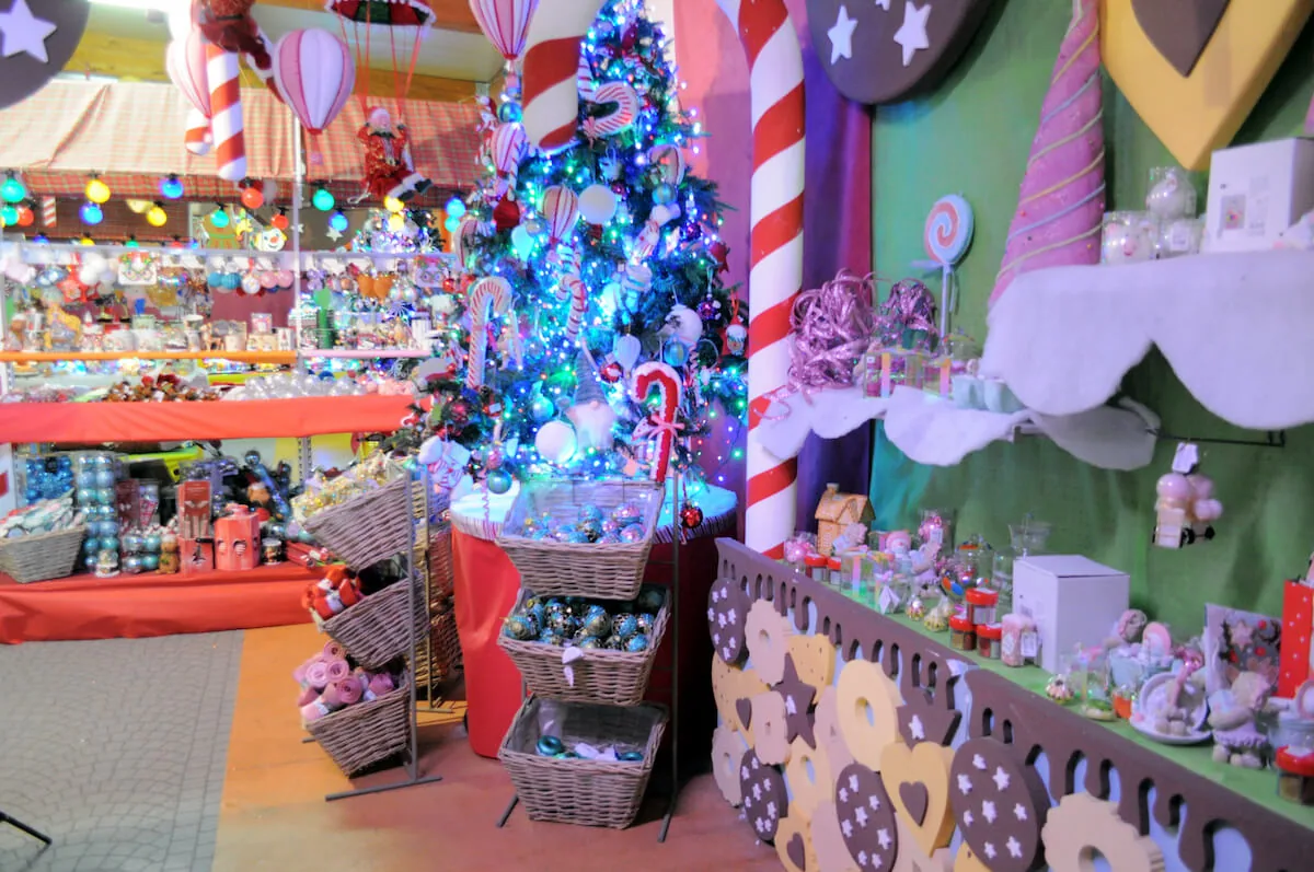 Reparto colorato con alberi addobbati di bastoncini e caramelle, cesti di peluche e pareti a biscotto