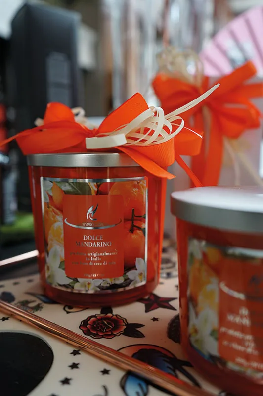 Candele profumate in barattoli di vetro arancione con fiocchi di rafia, su un vassoio decorato