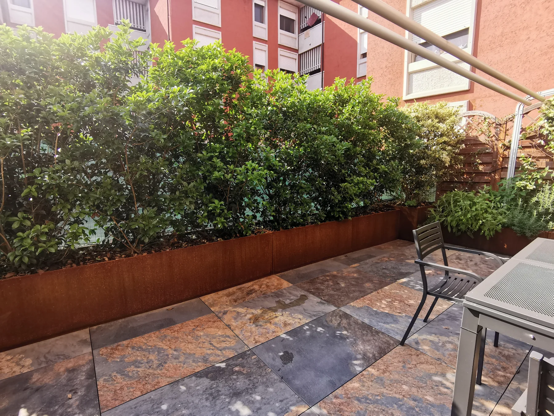Terrazzo in lastre di ardesia chiuso da una siepe fitta in fioriere di corten
