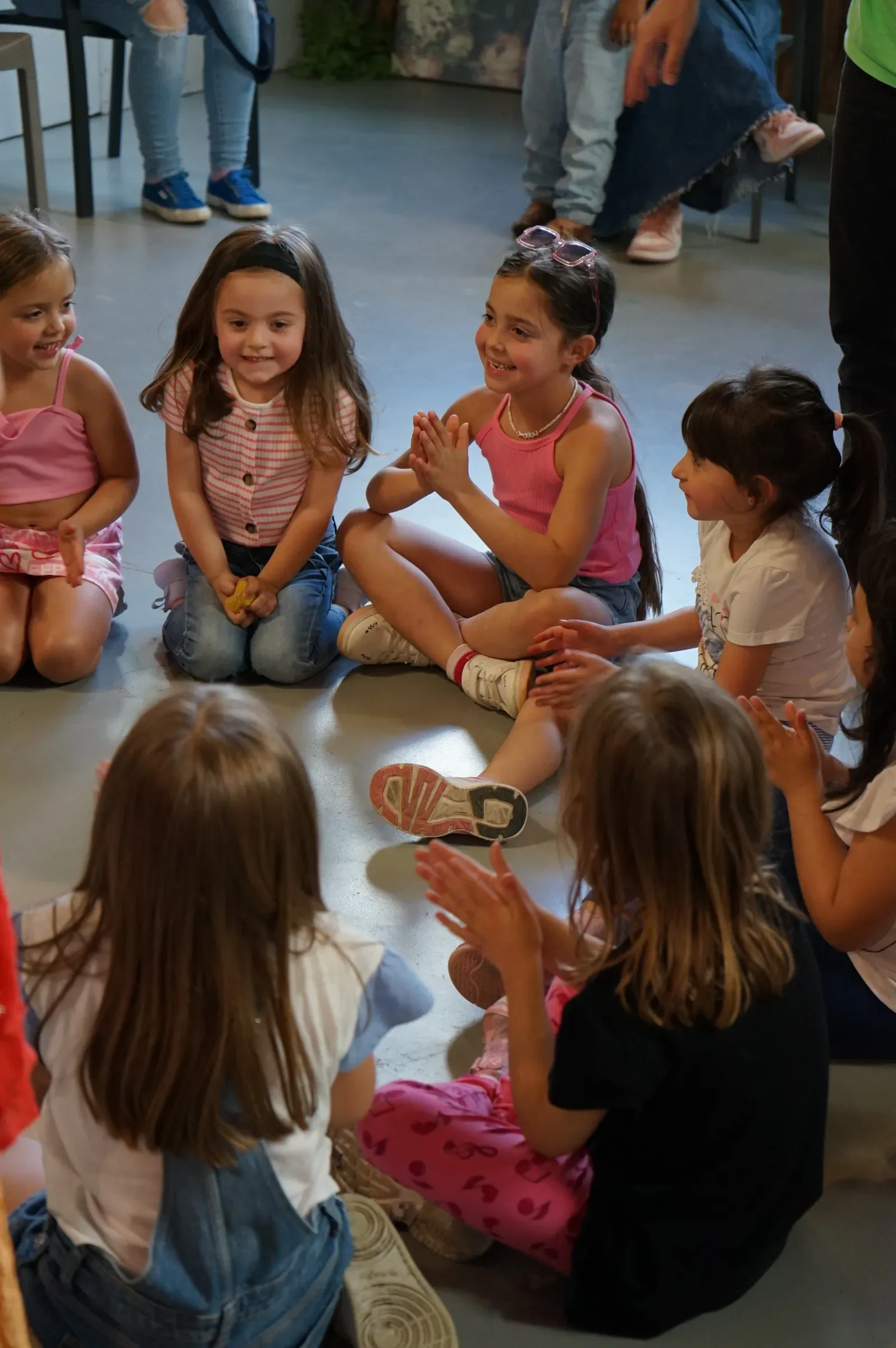 Bambine sedute a gambe incrociate sul pavimento che sorridono e battono le mani