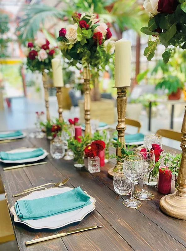 Coperto con il tovagliolo verde acqua e i candelieri dorati con rose rosse