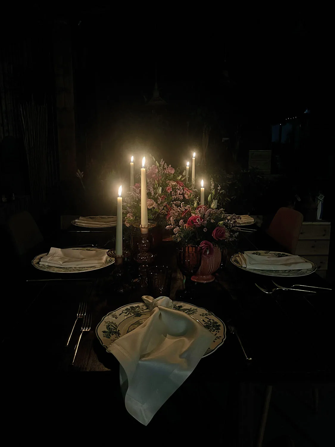 La tavola di sera, illuminata soltanto dalle candele accese fra i fiori