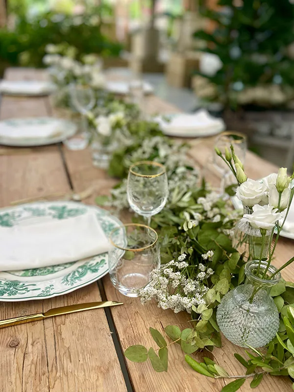 Corsia di fiori bianchi ed eucalipto fra i piatti a decoro verde