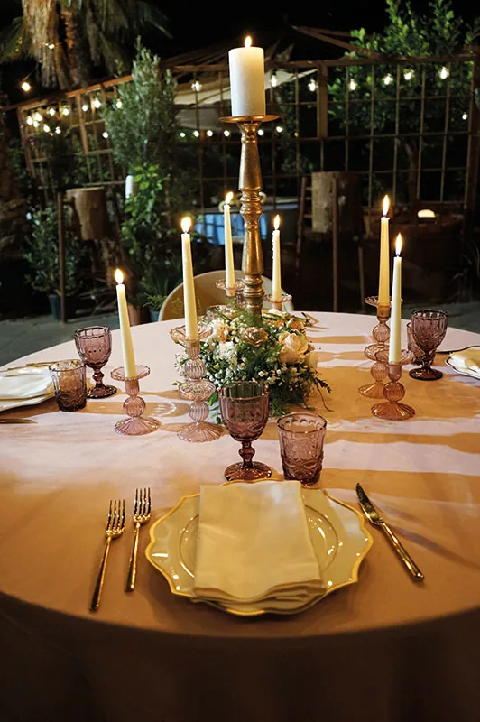 Candelabro dorato e roselline al centro della tavola rosa, di sera