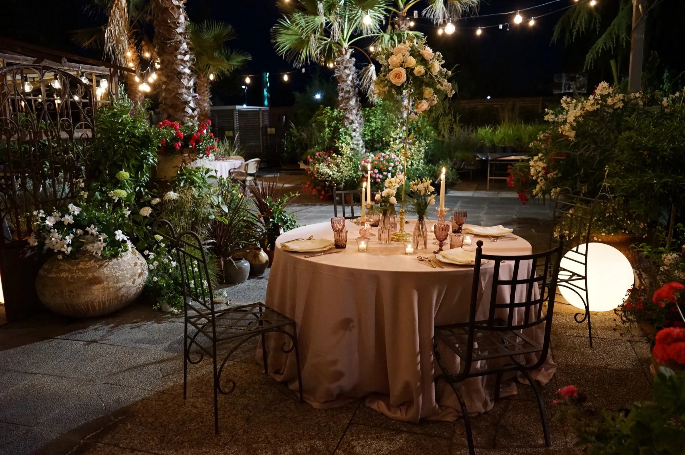 Tavola nuziale di sera tra candele, fiori e luminarie, allestita da Sinflora